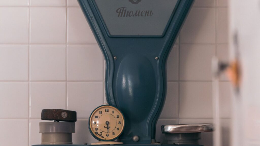 A vintage kitchen scale with a clock face standing on a counter