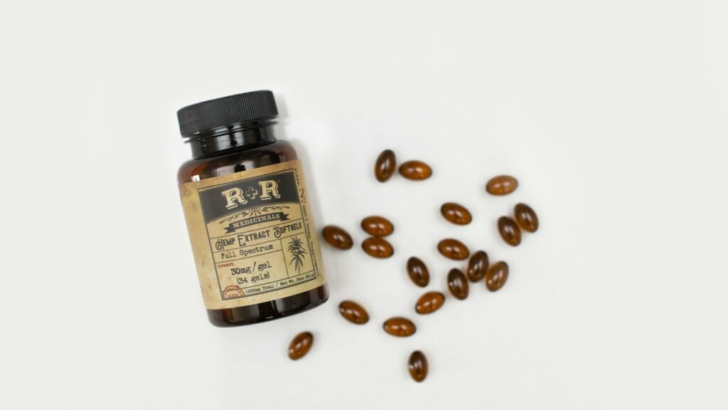 A supplement bottle with amber capsules spilled across a white surface