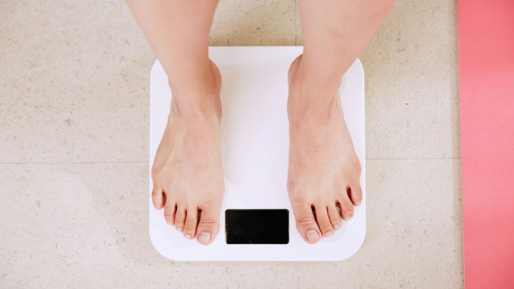 Overhead view of bare feet standing on a white digital bathroom scale